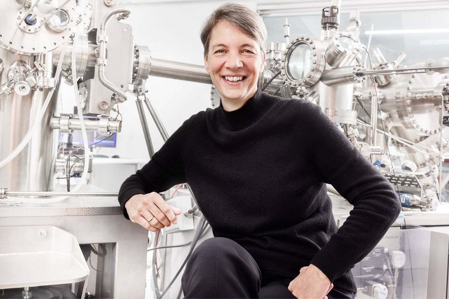 Professor Michelle Simmons is pictured in a black long sleeved top and pants, surrounded by shiny metallic equipment in a university lab.