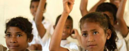 Image of students with their hands up in a classroom
