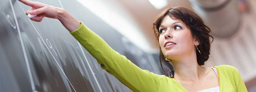 Woman in green pointing at chalkboard
