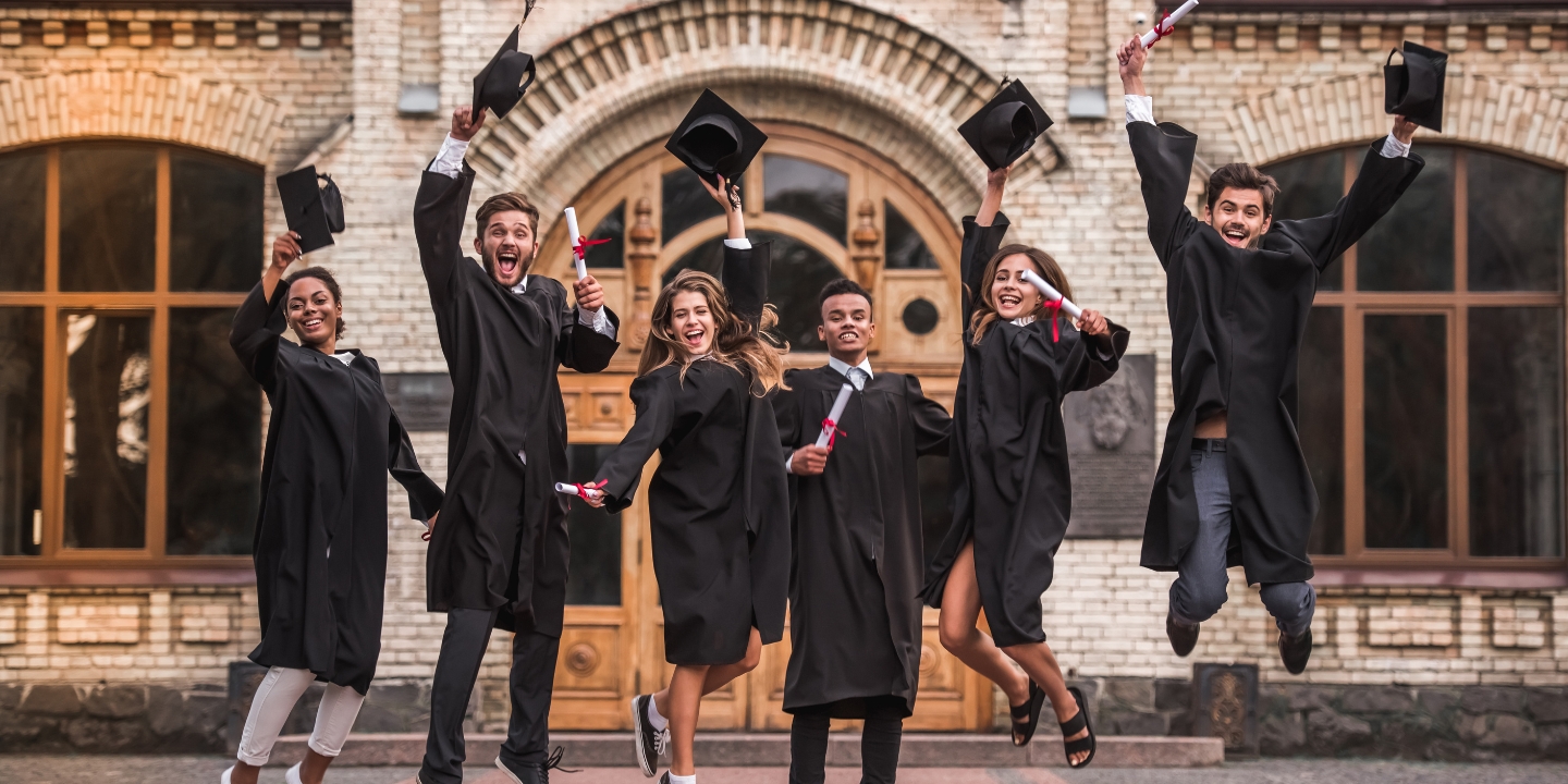 Six young adult students in university graduation gowns leap in the air, throwing their caps