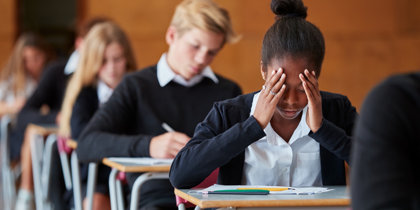 Stock image of an anxious teenage student sitting an examination in a school hall.