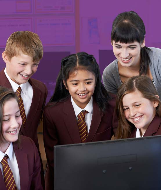 A group of young highschool girls and boys looking at a computer screen with a teacher looking over their shoulder