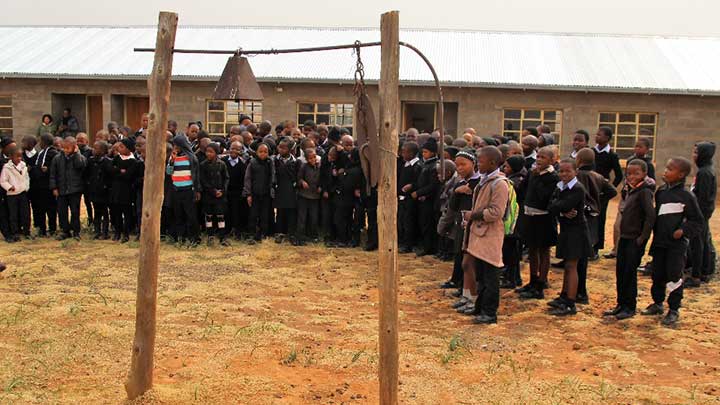 Children outside of classroom, next to school bell in the Kindom of Lesotho