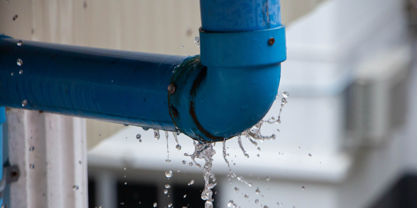 Stock image: Closeup view of leaked and splash water from the plastic pipe during the rainy day after storm.