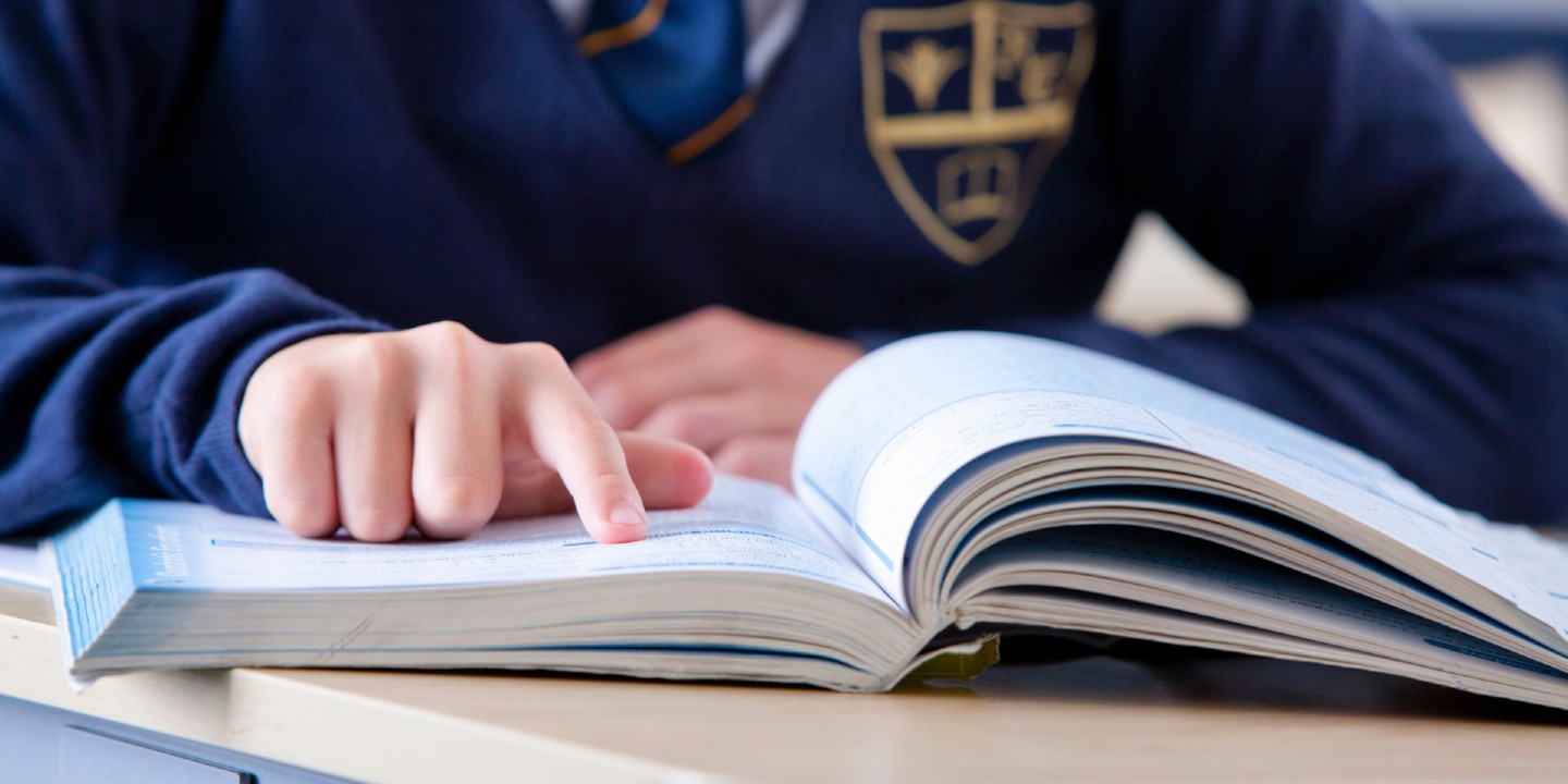 A close up stock image of a student's fingers pointing on a page of a book.