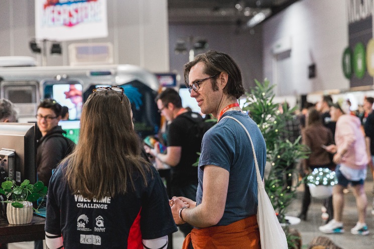 Two people in conversation at the STEMGAMES stand at PAX 2018, Melbourne, Australia