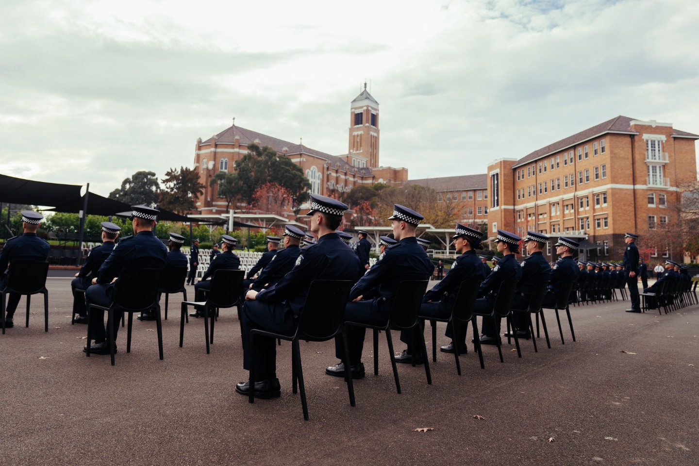 Police recruits sit facing away from the camera at a graduation ceremony at the Victorian Police Academy